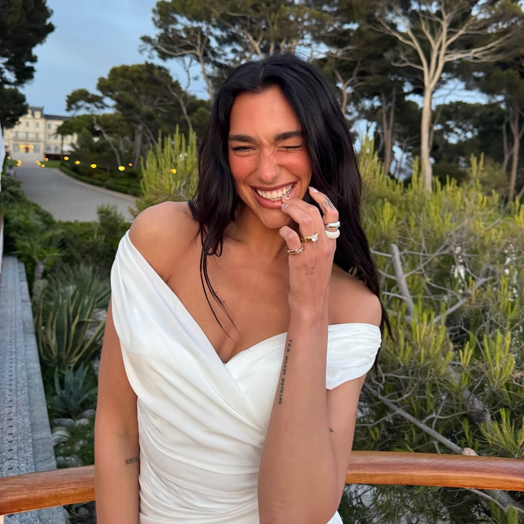 Image may contain dua lipa brunette hair head face accessories jewelry ring adult dimples and happy